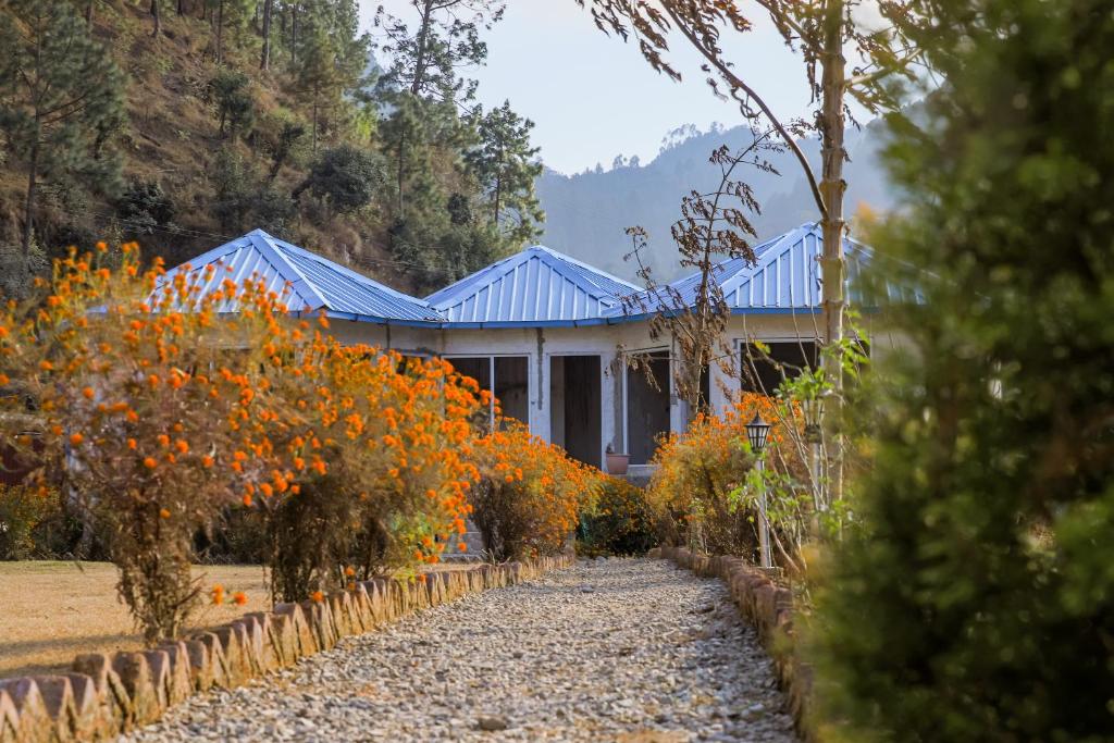 a house with a blue roof and some orange flowers at Blossom Bliss Resort in Bhīm Tāl