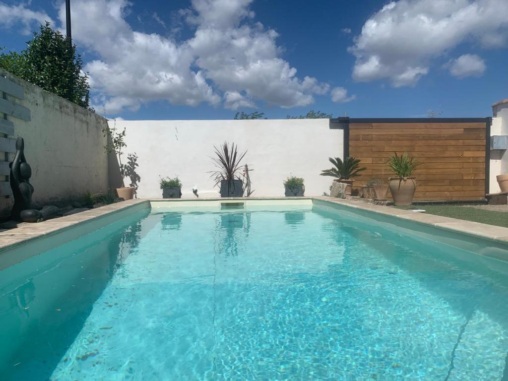 a swimming pool with blue water in a backyard at YOGAILO maison de charme in Colombiers
