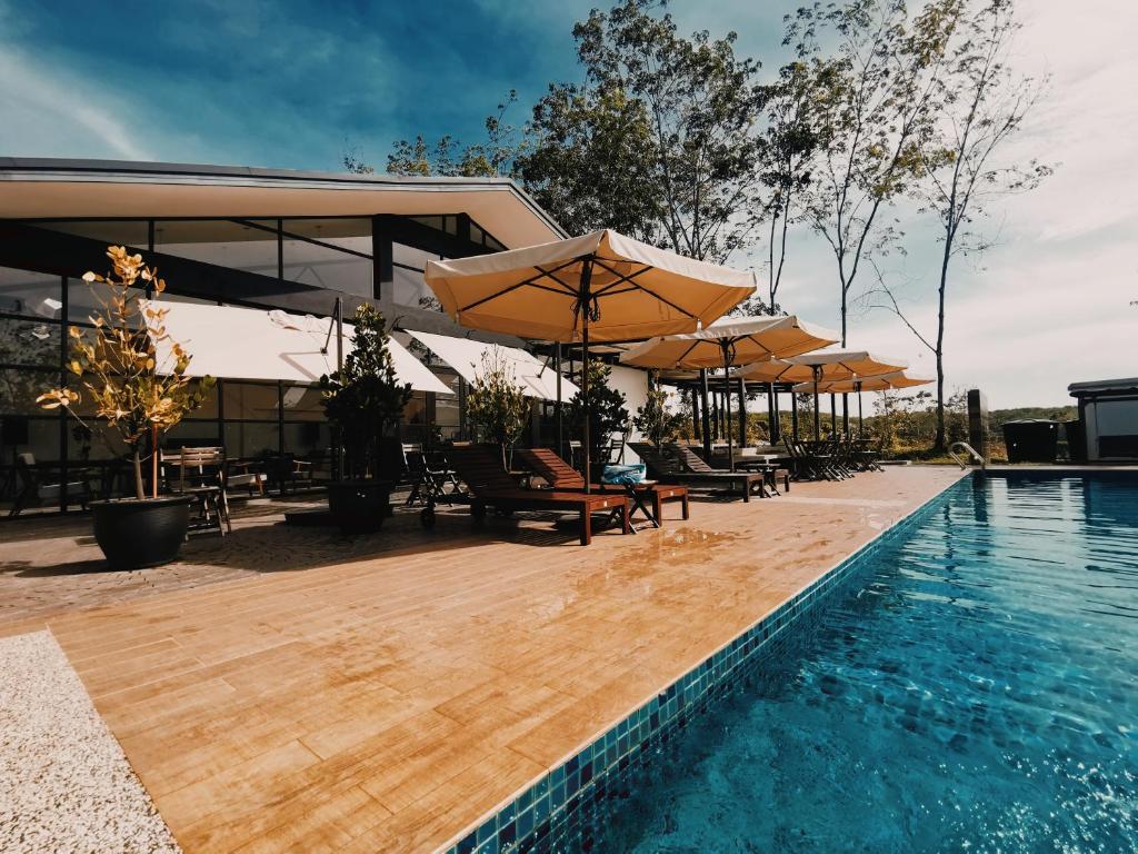 - une piscine avec des parasols, des tables et des chaises à côté d'un bâtiment dans l'établissement The Rubber Escape, Melaka, à Malacca