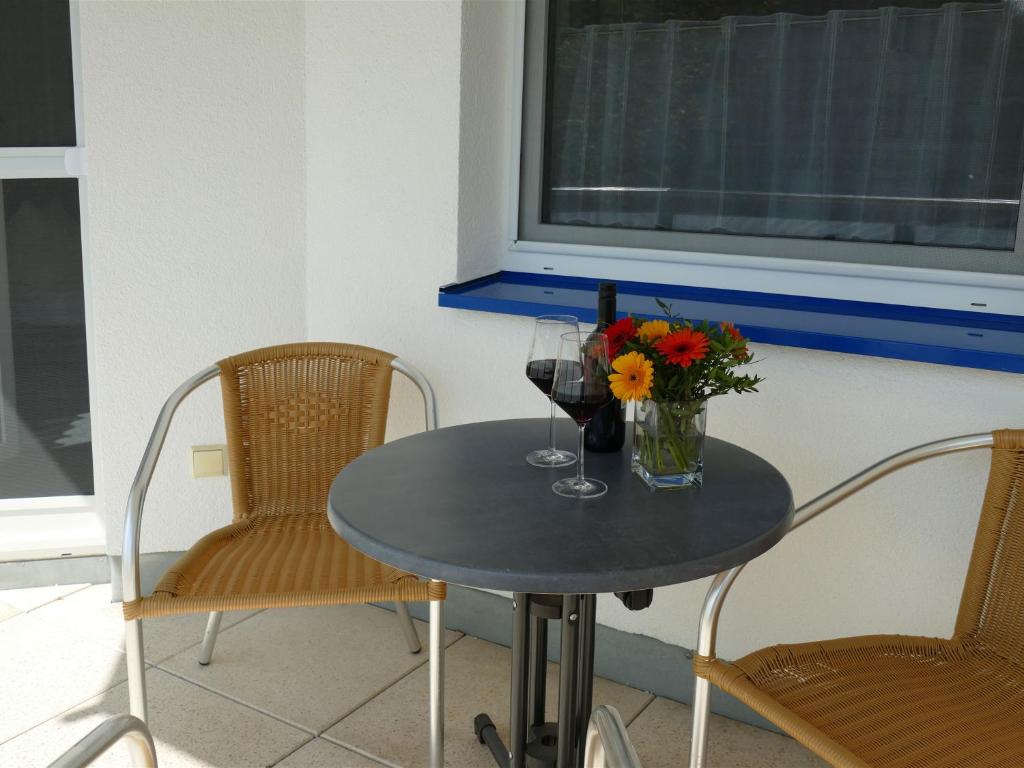 a table with two chairs and a vase of flowers on it at Pension Maiglöckchen in Karlshagen