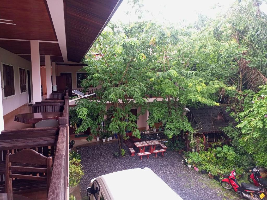 a porch of a house with a tree and benches at Phamarn View Guesthouse in Ban Nahin-Nai