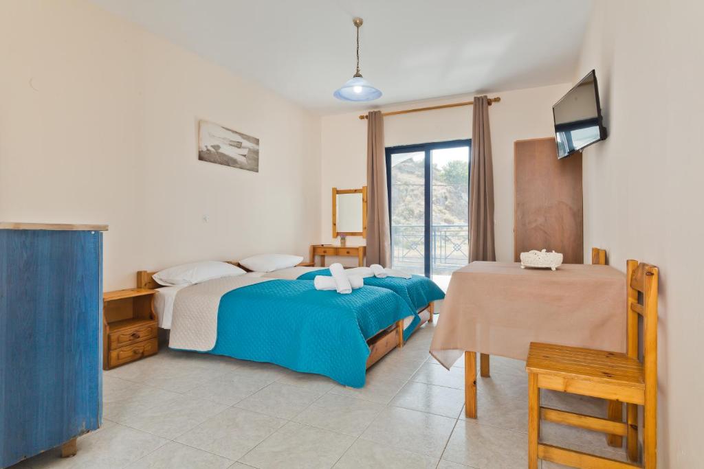 een slaapkamer met een bed, een tafel en een televisie bij Venetia Studios in Karpathos