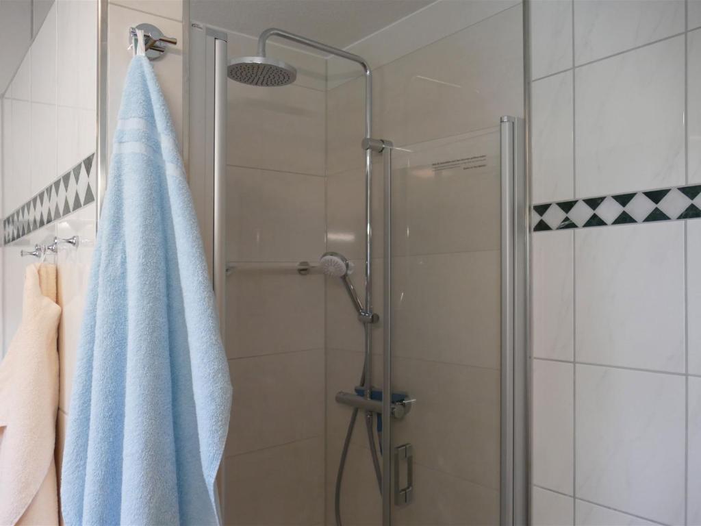 a bathroom with a shower with a blue towel at Pension Maiglöckchen in Karlshagen