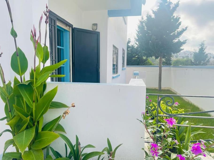 a white building with a blue door and some plants at Superbe maison à M'diq in M'diq