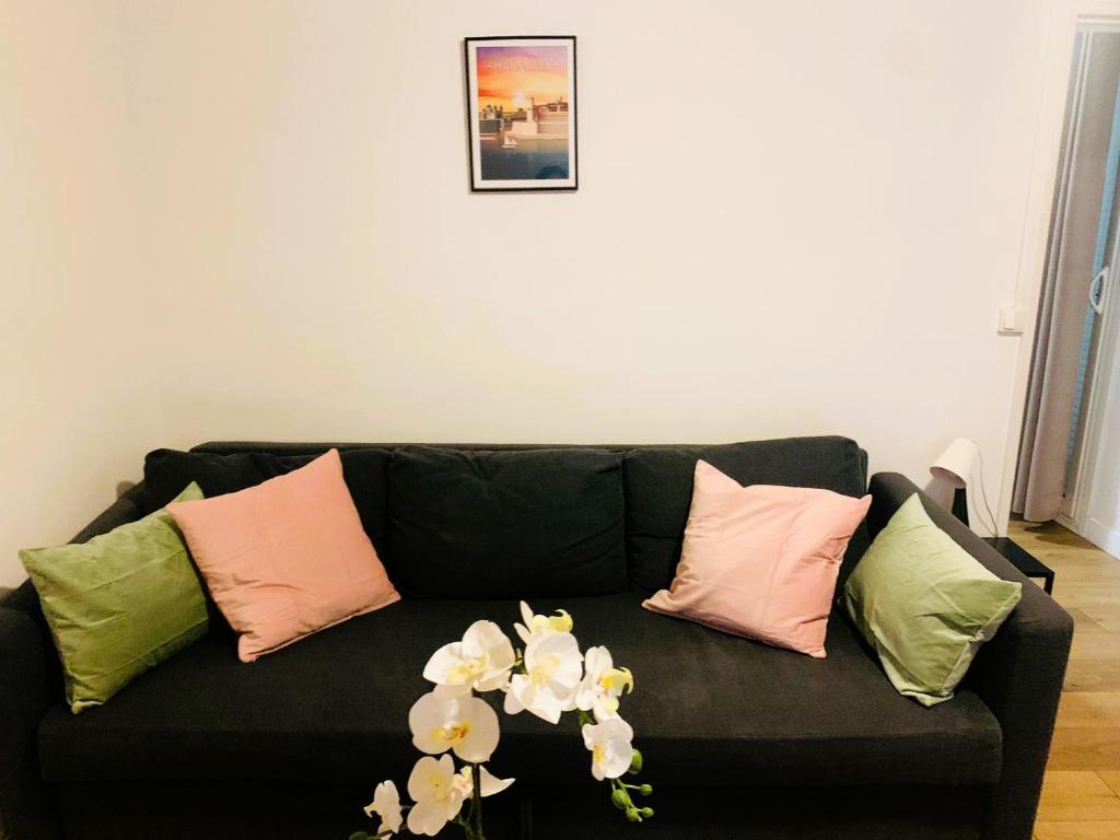 um sofá preto com almofadas e flores em Great place near Vieux Port em Marselha