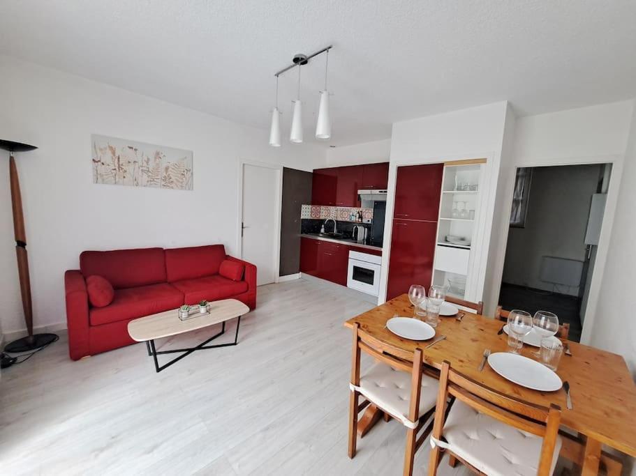 een woonkamer met een rode bank en een tafel bij Le Colibri - Appartement 4 à 6 couchages avec terrasse in Allemont
