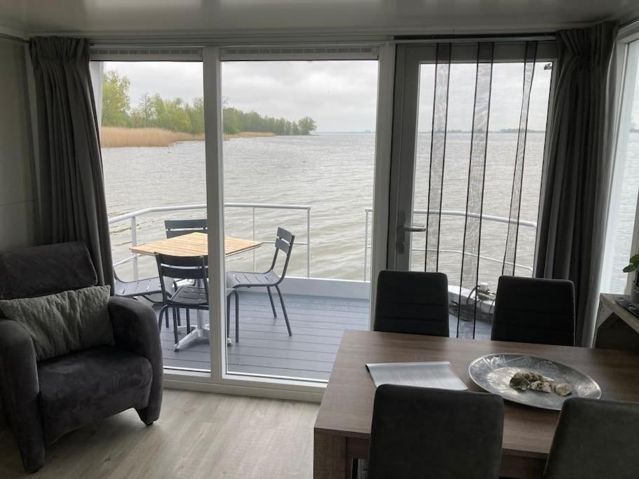 uma sala de estar com vista para a água em Houseboot Kingfisher, lake view em Biddinghuizen