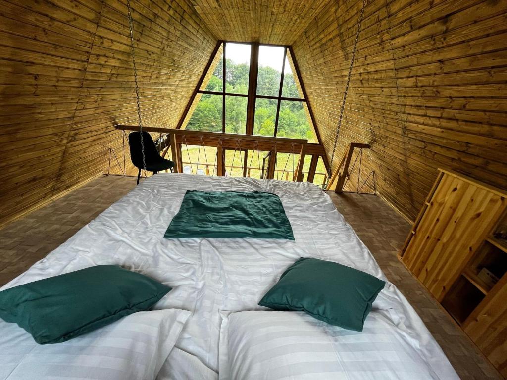 a large bed in a wooden room with a window at Dealu din Vale in Ponor