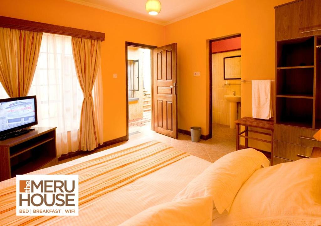 a bedroom with an orange house with a bed and a television at The Meru House in Nkubu