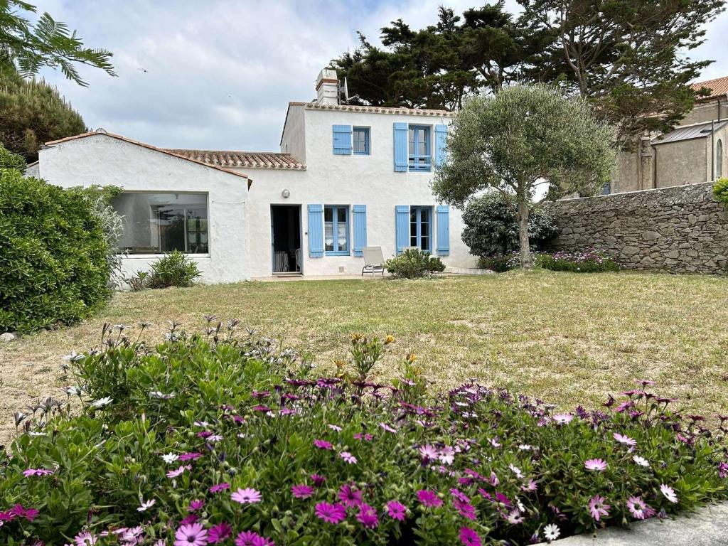 a house with blue windows and flowers in the yard at Maison Noirmoutier-en-l'Île, 4 pièces, 6 personnes - FR-1-224B-75 in Noirmoutier-en-l'lle
