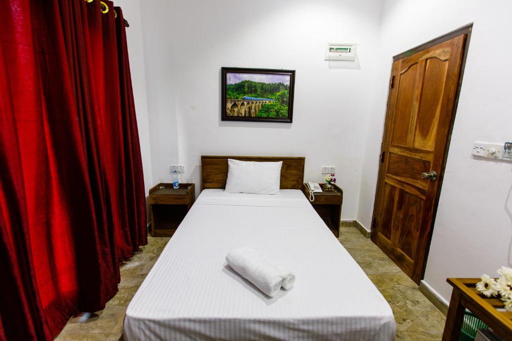 ein Schlafzimmer mit einem Bett und einem roten Vorhang in der Unterkunft Pearl Island Inn in Jaffna