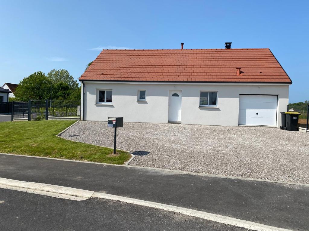 une maison blanche avec un toit rouge et un parking dans l'établissement Entre mer et campagne, à Campigneulles-les-Grandes