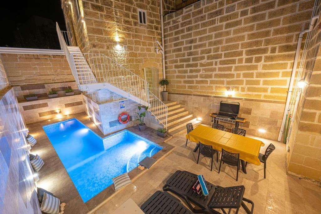 a patio with a pool and a table and chairs at Tal-Andar Farmhouse in Kerċem