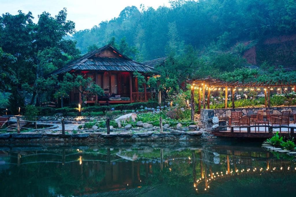 un complexe avec un étang et un bâtiment éclairé dans l'établissement Natalie's Villa & Resort Moc Chau, à Mộc Châu