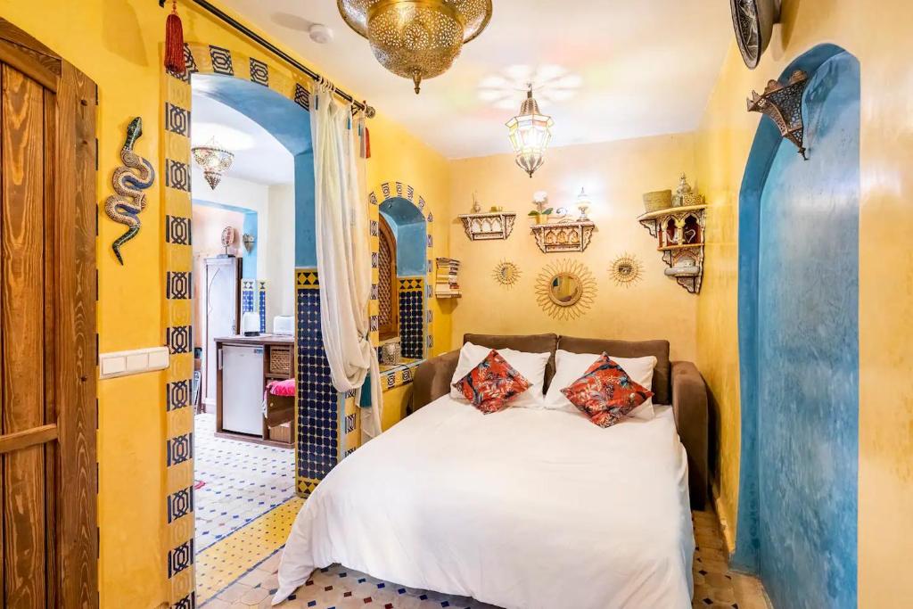 a bedroom with a white bed and yellow walls at Dar Sandra Moroccan Tiny House in Tangier