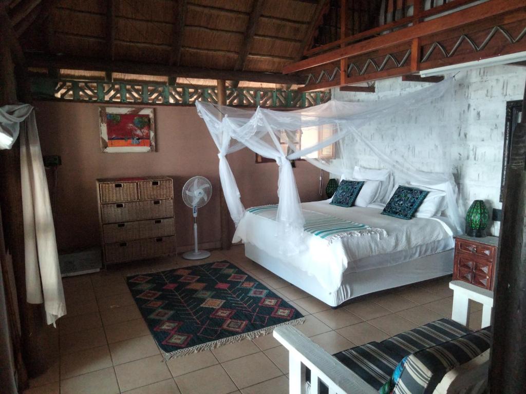 a bedroom with a bed with a mosquito net at Shongili Island Lodge in Vila Praia Do Bilene