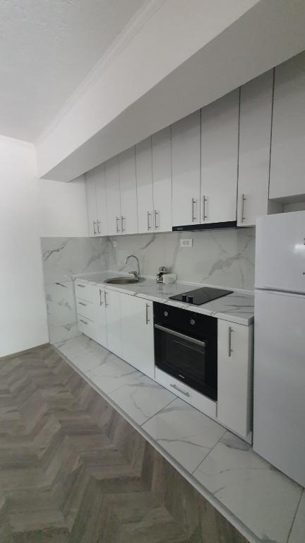 a kitchen with white cabinets and a black appliance at Flat in Trpejca in Ohrid