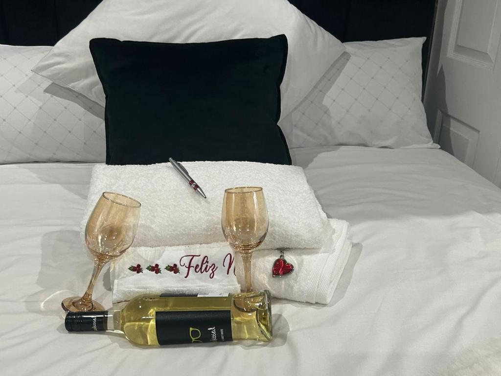 a bed with a bottle of wine and two glasses at Serenity Guest House in Soweto