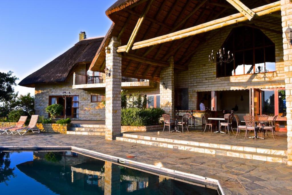 Inkungu Lodge في Champagne Valley: منزل به فناء ومسبح