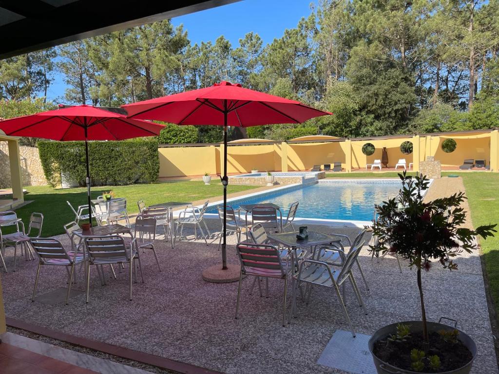 a group of tables and chairs with umbrellas next to a pool at Quinta Dos Amarelos no Meco in Aldeia do Meco