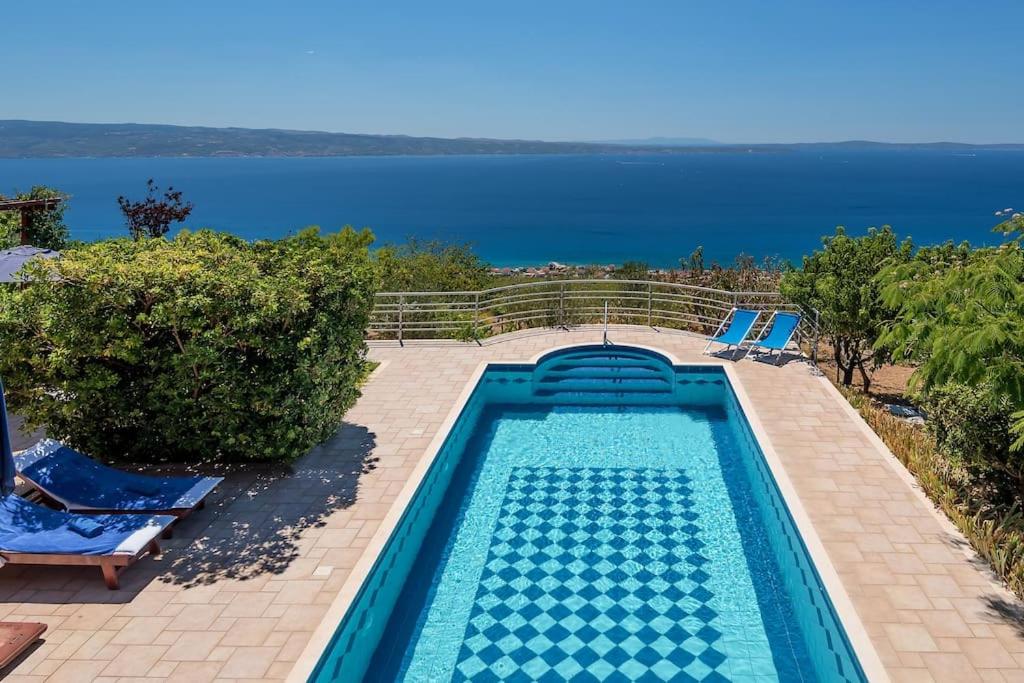 uma piscina com cadeiras e o oceano ao fundo em Villa Aquarius, Podstrana, Croatia em Podstrana