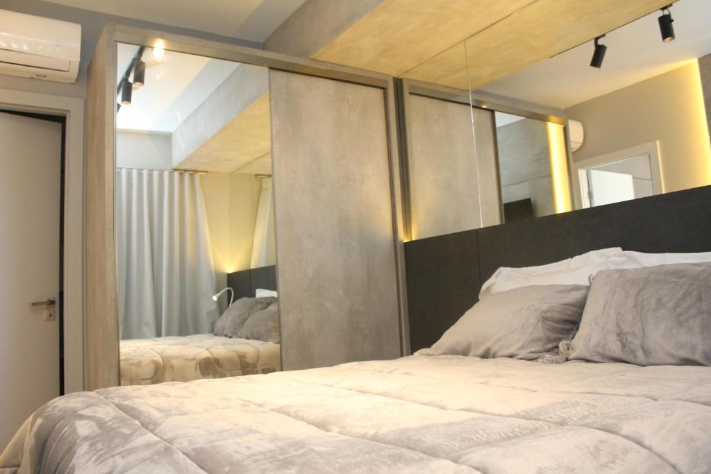 una camera da letto con un grande letto e un grande specchio di MyHome - Suíte de Luxo próximo ao Shopping Iguatemi e Consulado Americano a Porto Alegre