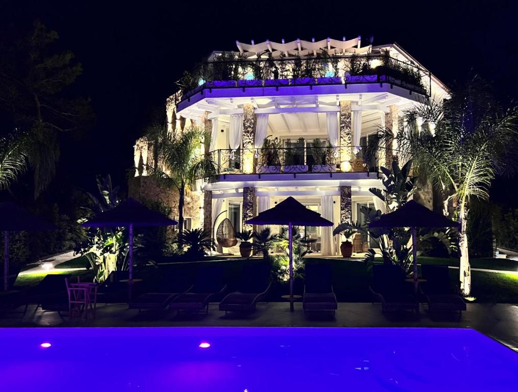 un edificio con una piscina di fronte ad essa di notte di Villa Aquamarina Pavoncella Rossa a Porto Pino