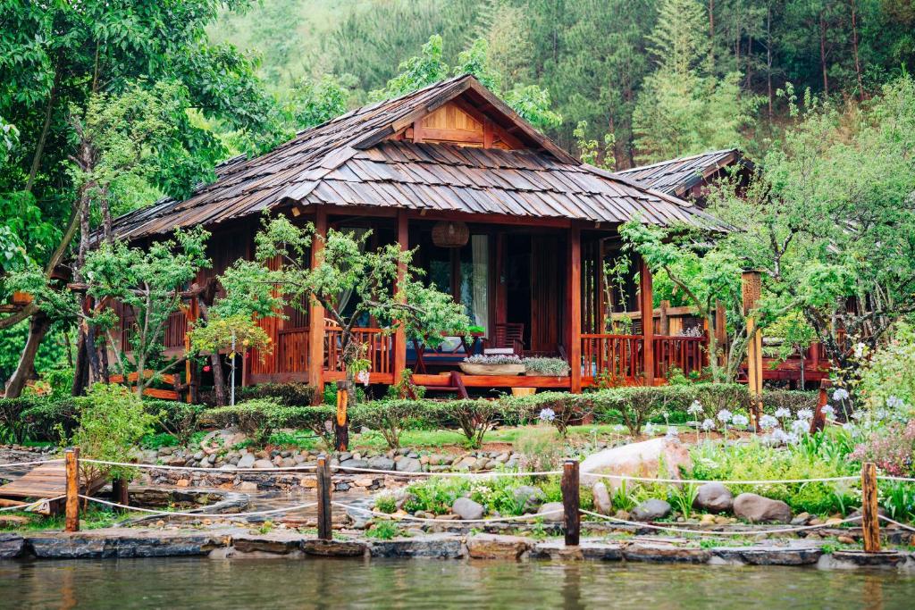 una casa en el bosque al lado de un cuerpo de agua en Natalie's Villa & Resort en Mộc Châu