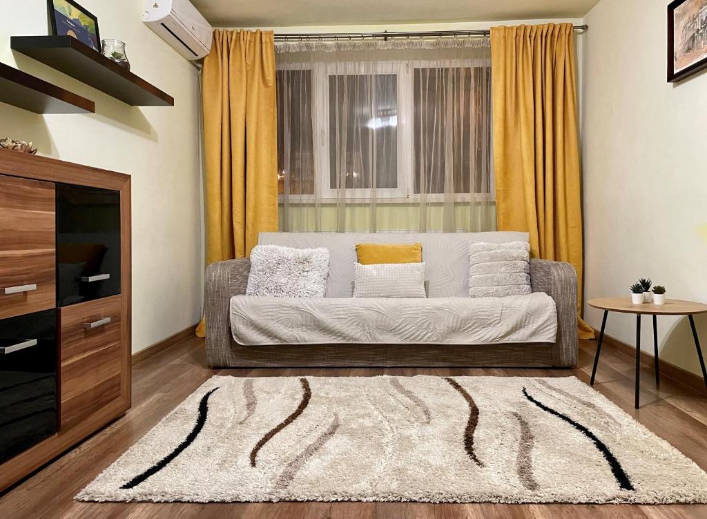 uma sala de estar com um sofá e uma janela em Cozy and Clean Apartment, near National Arena em Bucareste