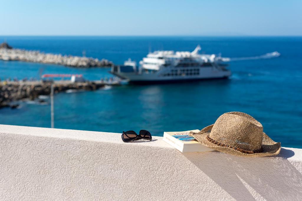 a hat and book on a ledge with a cruise ship at Sofia's Lovely Rooms in Hora Sfakion