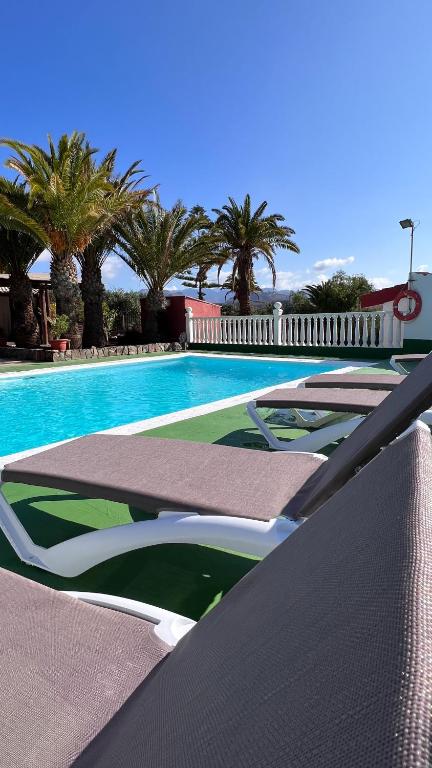 a swimming pool with several chairs and palm trees at Salobre Blue Sky 1 in Salobre