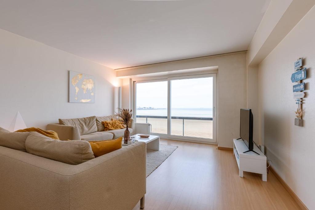 a living room with a couch and a television at Stunning Seaview apt on 7th floor at beachfront in Knokke-Heist