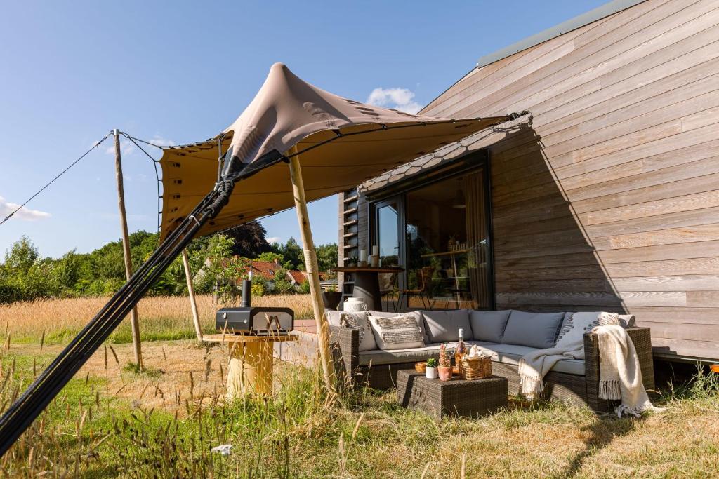 a couch under a tent in a field at Tiny House nabij Brugge in Beernem