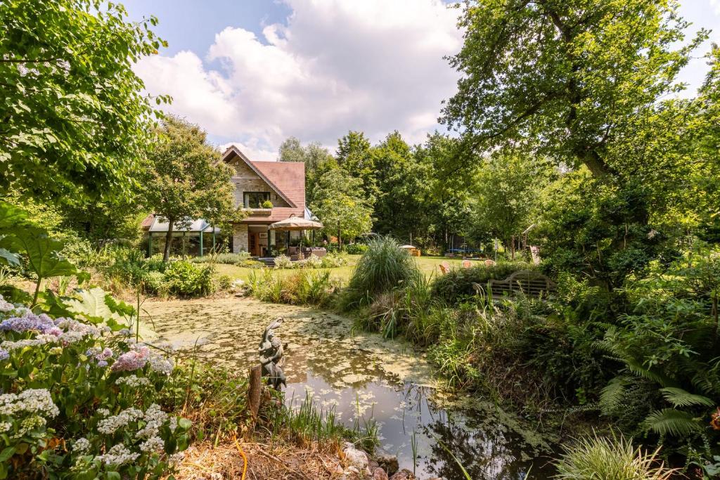 un jardín con un arroyo frente a una casa en Peacefully located villa with stunning garden and hot tub, en Oostkamp