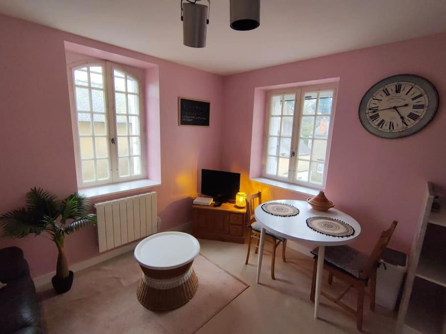 uma sala de estar com uma mesa e um relógio na parede em Cosy'Appart hyper centre Josselin em Josselin
