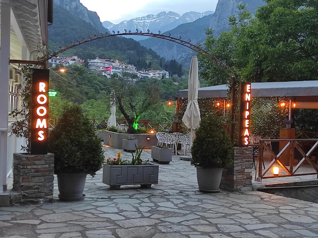 un restaurant avec un parasol, des chaises et un panneau dans l'établissement Ενοικιαζόμενα Δωμάτια Ενιπεύς- Rooms Enipeas, à Litochoro