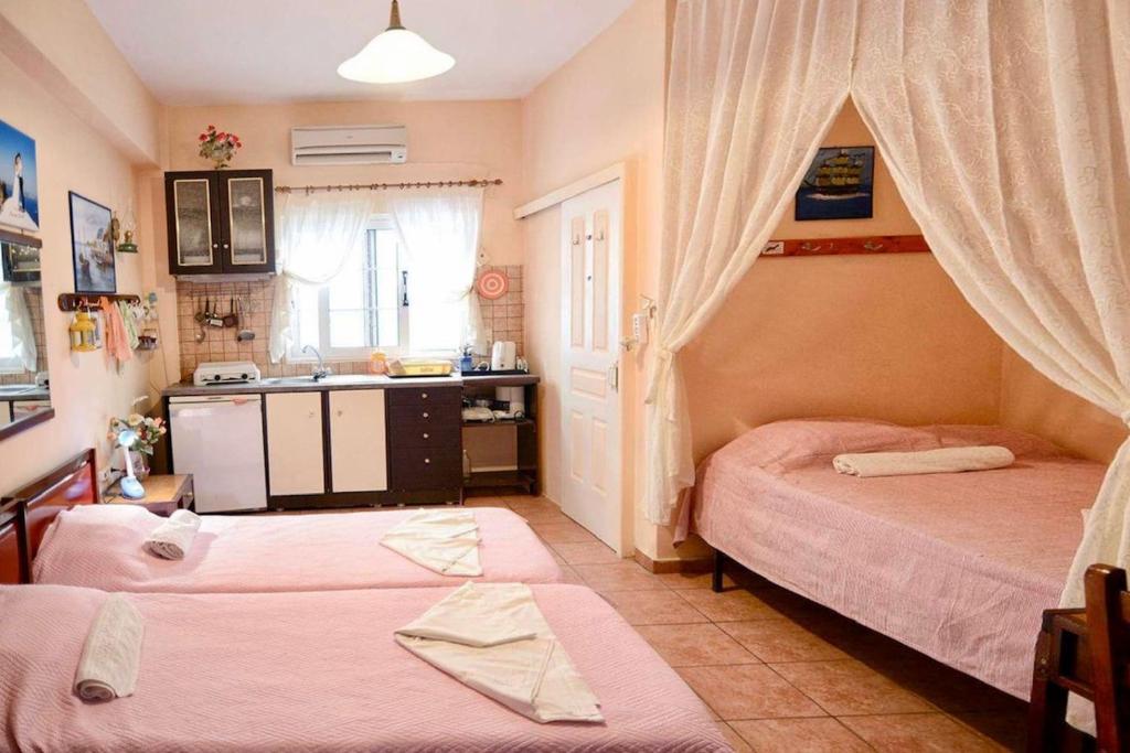 a bedroom with two beds and a kitchen with a sink at Ikaria Studios in Manganítis