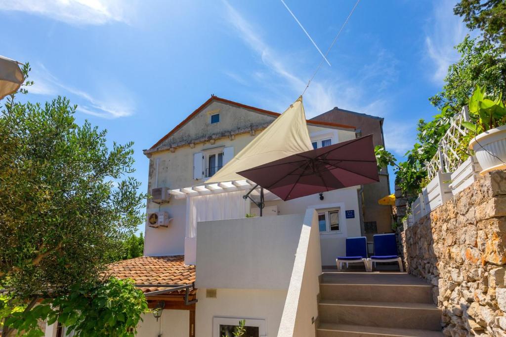 uma casa com um guarda-chuva na frente em Apartments Valeria, Mali Lošinj em Mali Lošinj