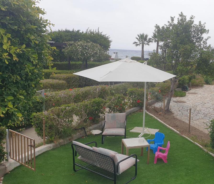 a patio with a table and chairs and an umbrella at Pampering Beach Dream, A Stunning Luxury Retreat in Meneou