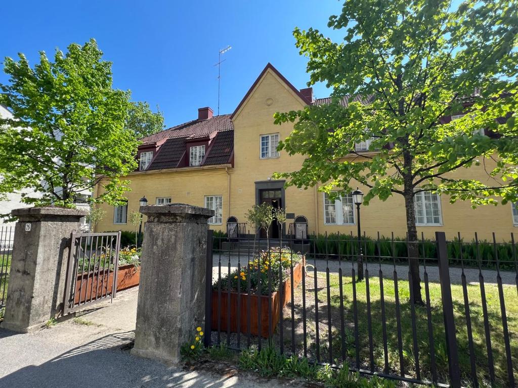 una casa amarilla con una valla delante de ella en Pappila Boutique Apartments en Jyväskylä