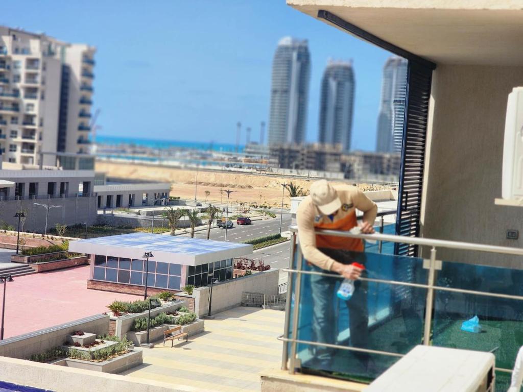 a man standing on the edge of a swimming pool at Apartment at El Down Town New El Alamein in El Alamein
