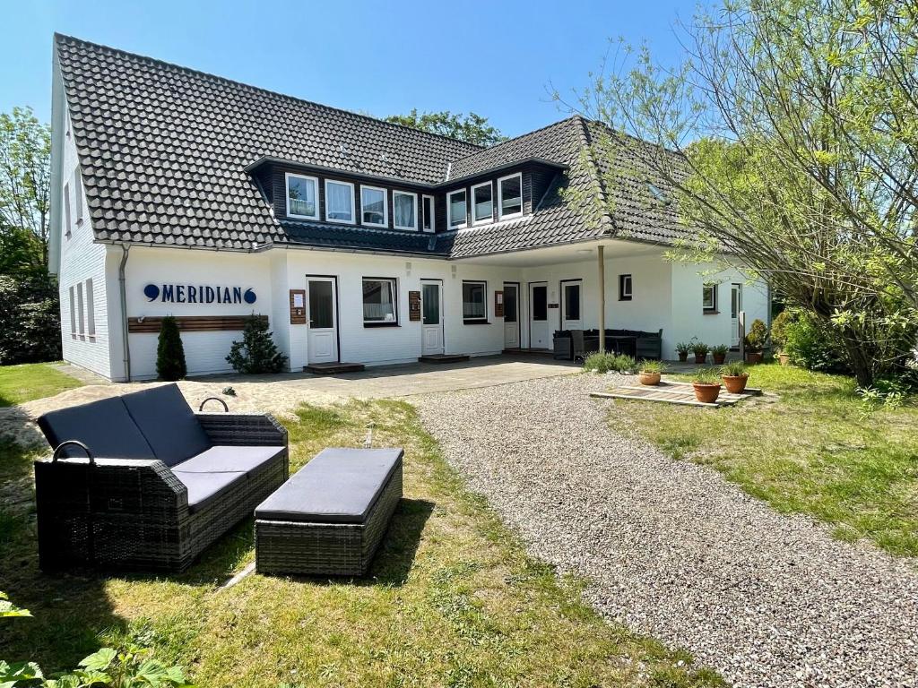 Una gran casa blanca con un sofá en el patio en Appartementhaus Meridian, en Sankt Peter-Ording