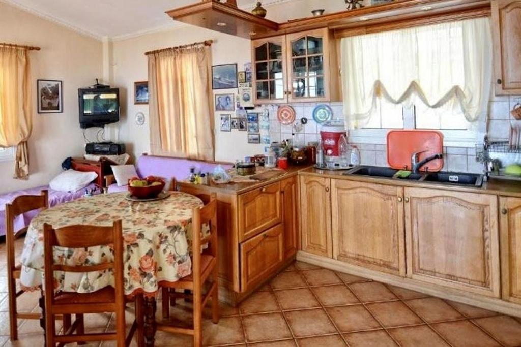 a kitchen with wooden cabinets and a table and a dining room at Ikaria Studios in Manganítis