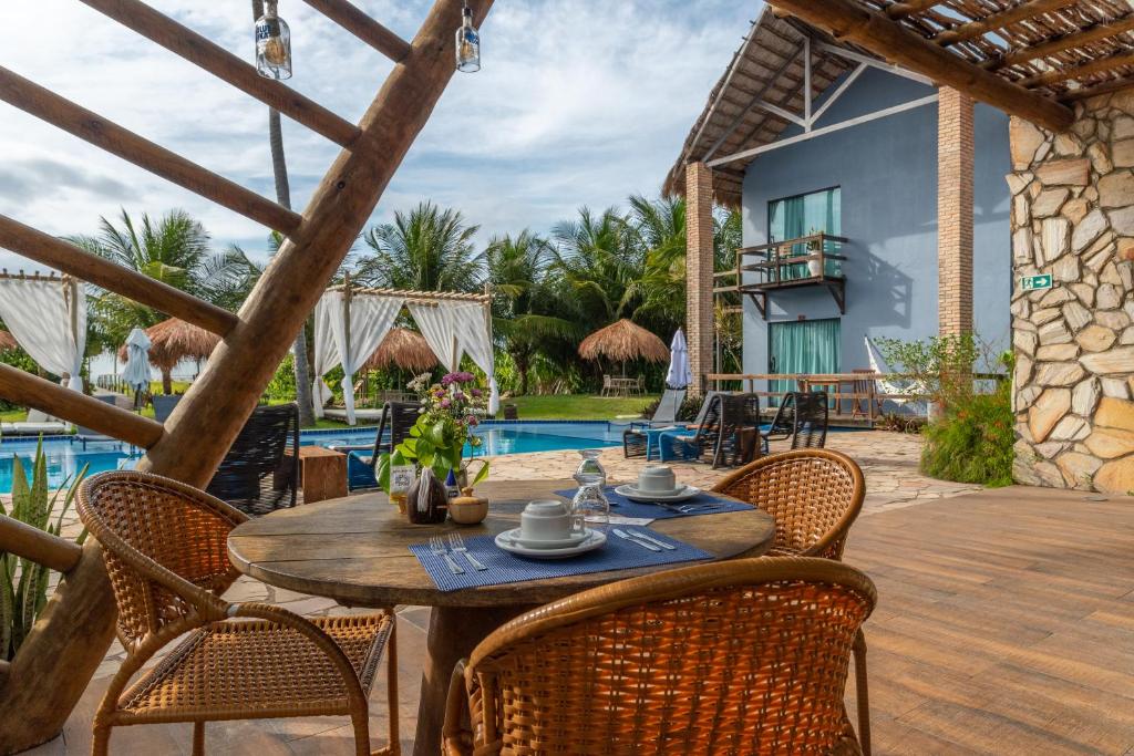 um pátio com uma mesa e cadeiras ao lado de uma piscina em Villa Pantai Milagres Exclusive Hotel em São Miguel dos Milagres