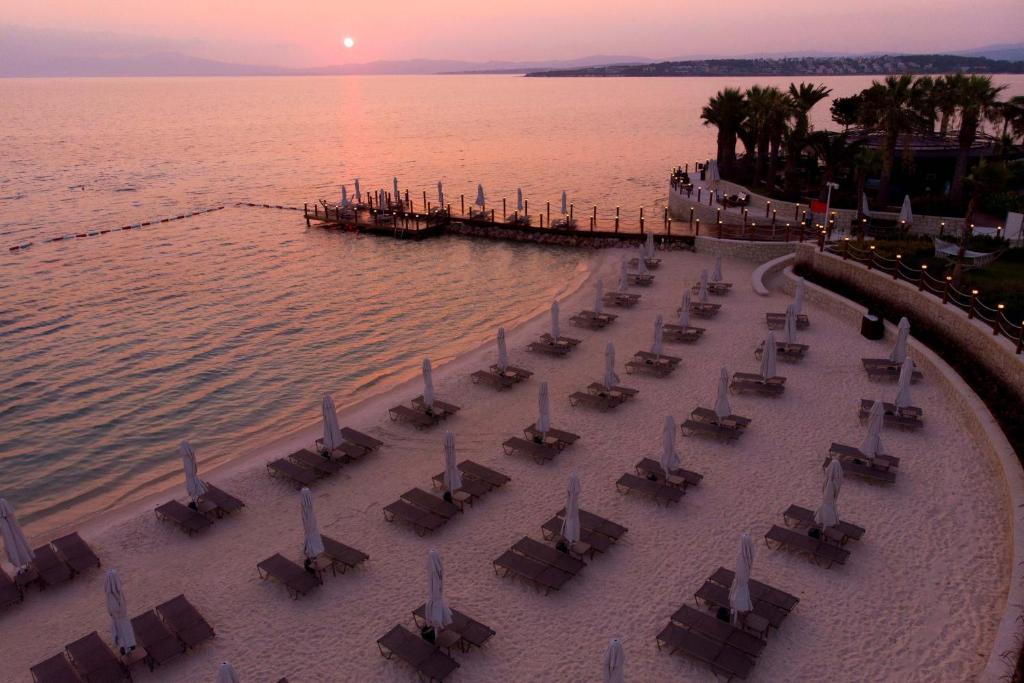 Reges, a Luxury Collection Resort & Spa, Cesme في تشيشمي: مجموعة طاولات وكراسي على شاطئ قريب من الماء