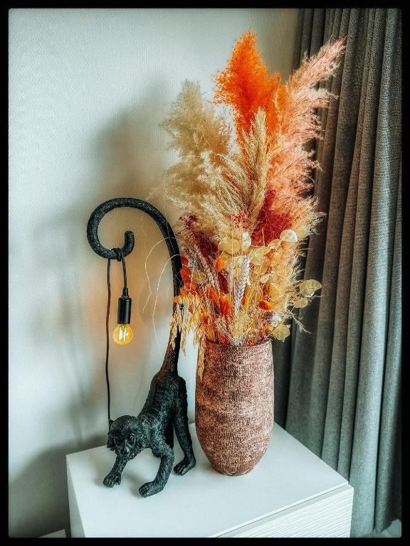 a vase with a cat sitting next to a plant at CASA MARE hartje Oostende met gratis parking in Ostend