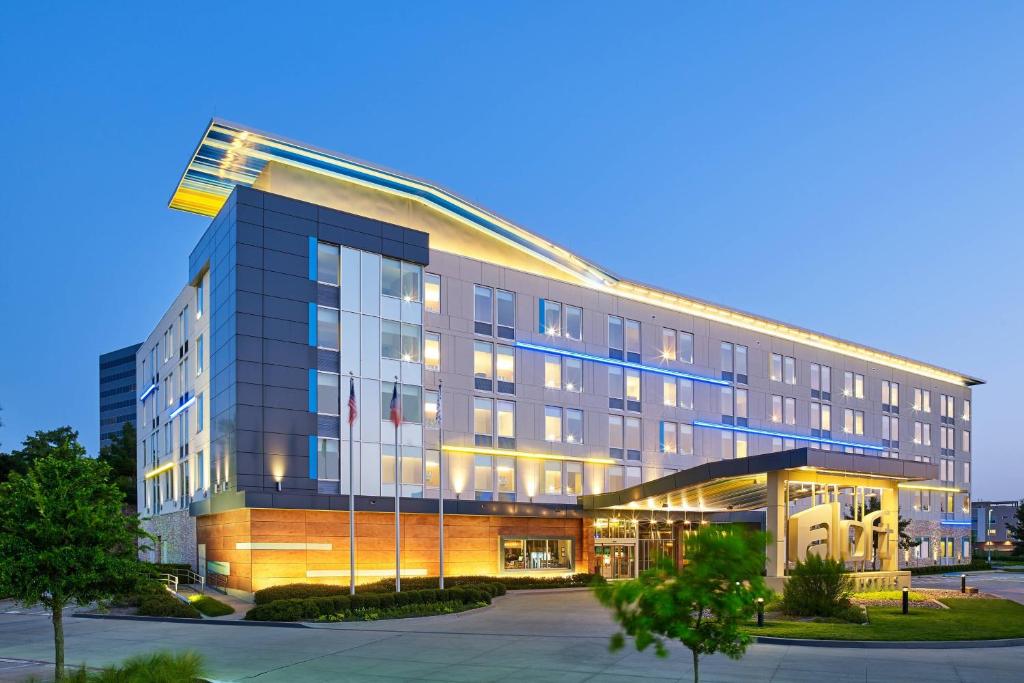 a building with a flag on top of it at Aloft Hotel Las Colinas in Irving