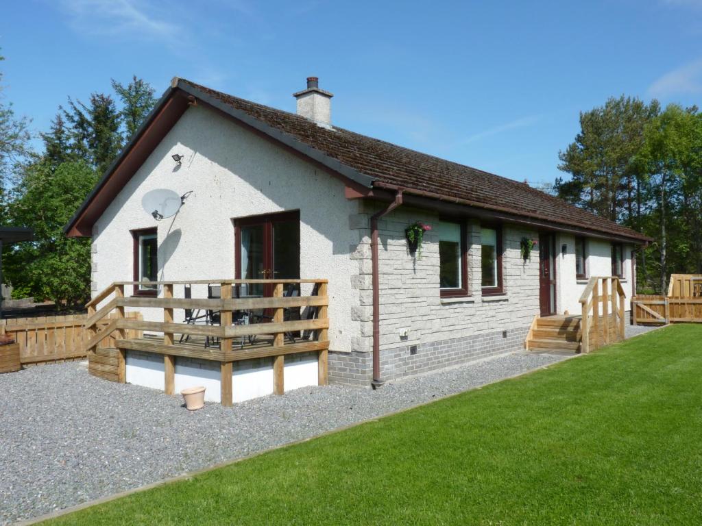 a small white building with a grass yard at Tanleys Guesthouse in Grantown on Spey