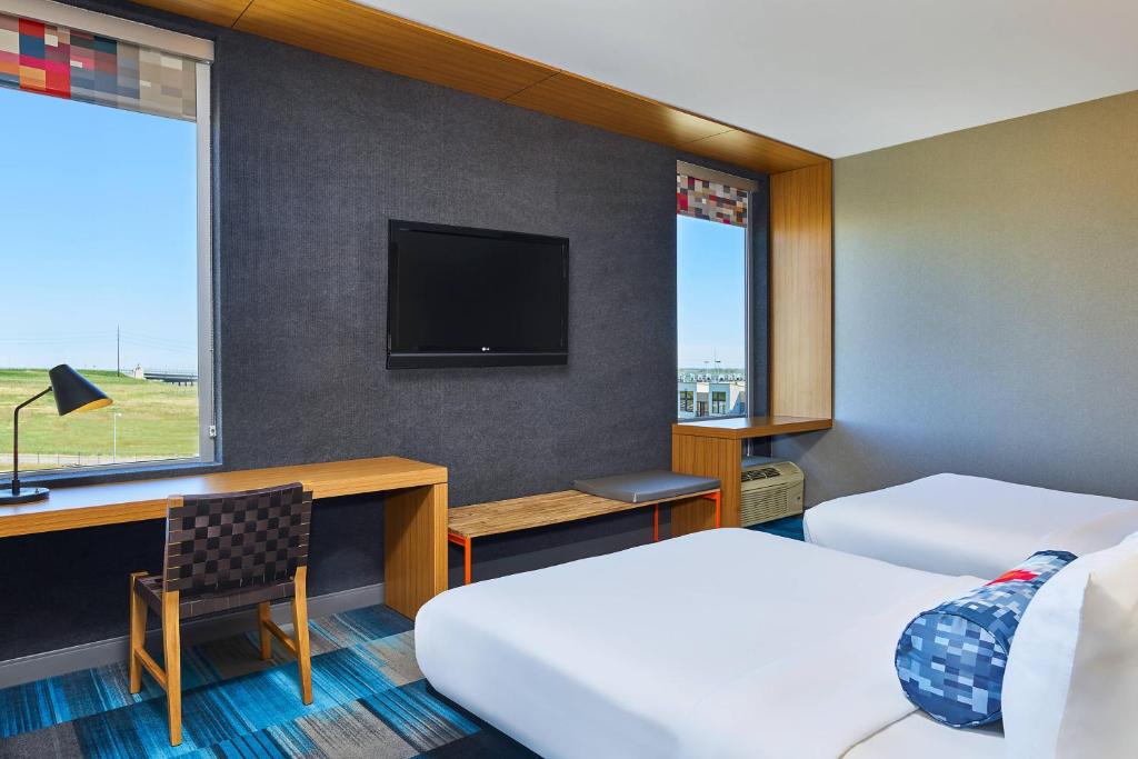 a hotel room with two beds and a desk and a tv at Aloft Broomfield Denver in Broomfield
