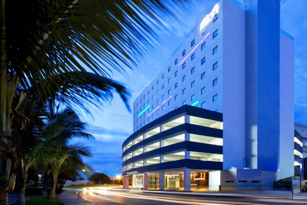 a large building with a palm tree in front of it at Aloft Cancun in Cancún